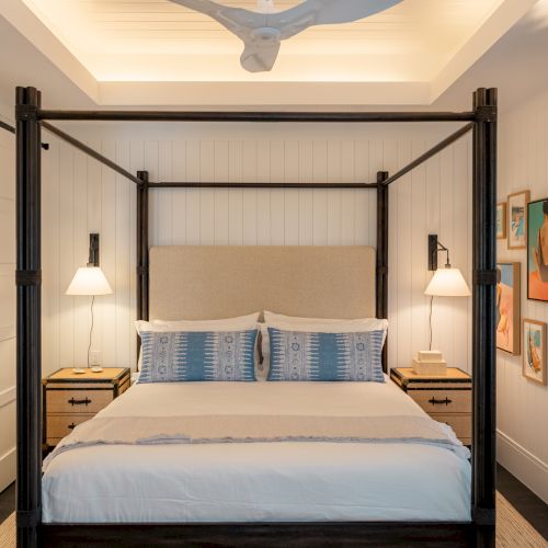 A modern, open-plan kitchen with a long island, gray and wood tones, pendant lights, and built-in appliances in a bright, airy space.